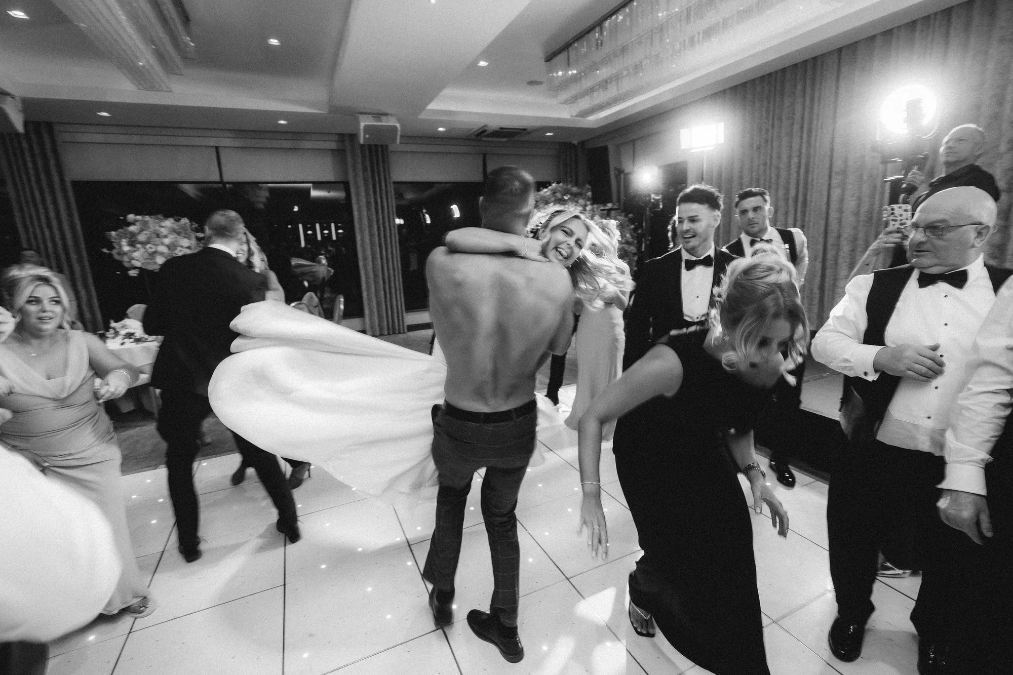 A joyful spin on the wedding dance floor, photographed in black and white.