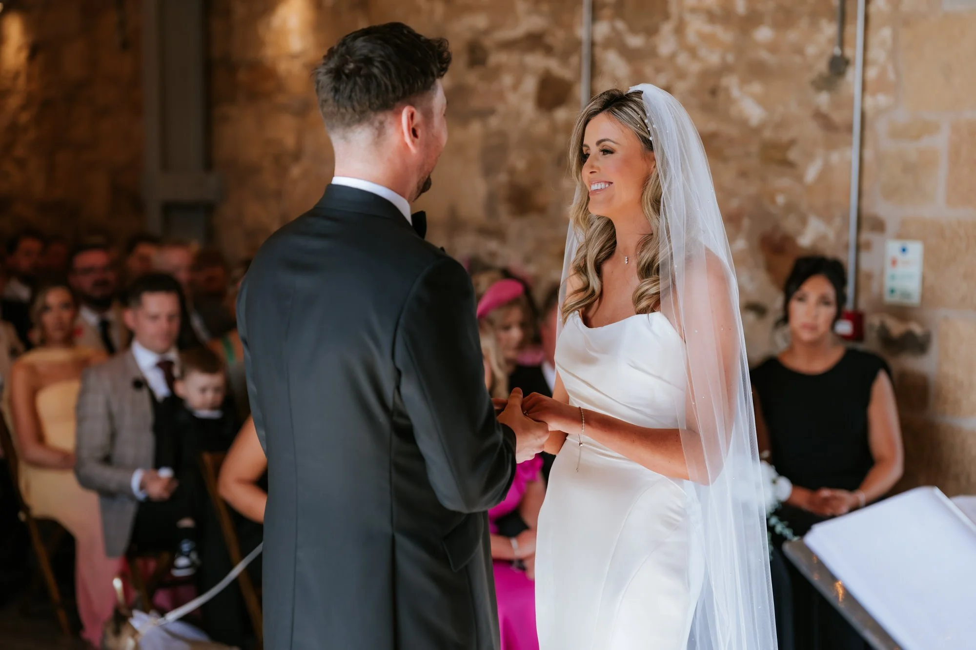 Natalie smiling while holding Jamie's hands during the ceremony