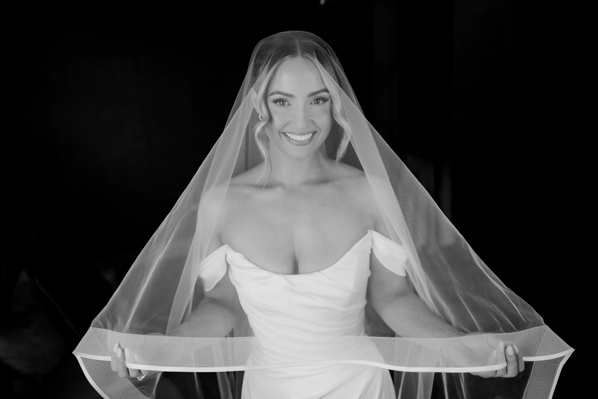 Black-and-white portrait of Elle smiling beneath her veil