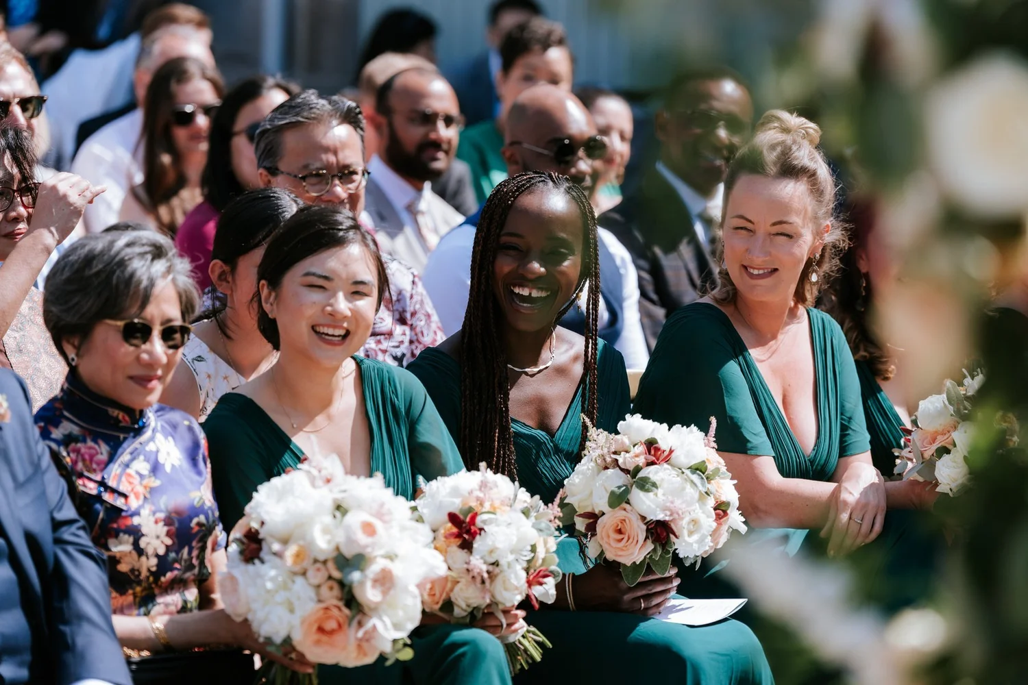 Guests and bridesmaids laughing during Kim and Kenneth’s outdoor wedding ceremony.