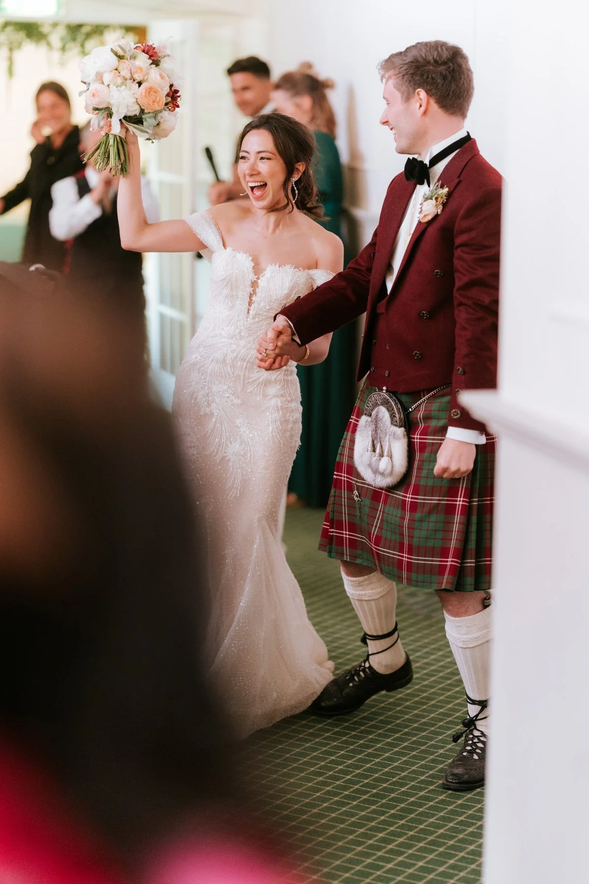 Kim raising her bouquet as she and Kenneth enter their wedding reception.