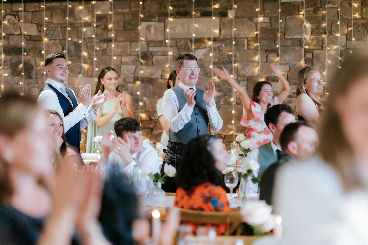 Guests standing with raised arms and applauding in Cairns Farm’s reception room.