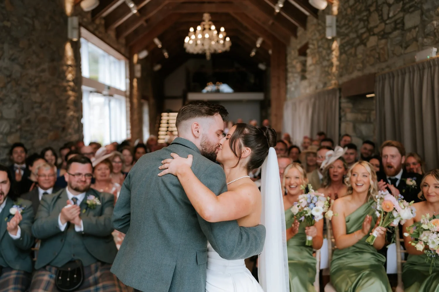 Lois and Dougie sharing their first kiss as their guests applaud beneath the timber beams at GG’s Yard.