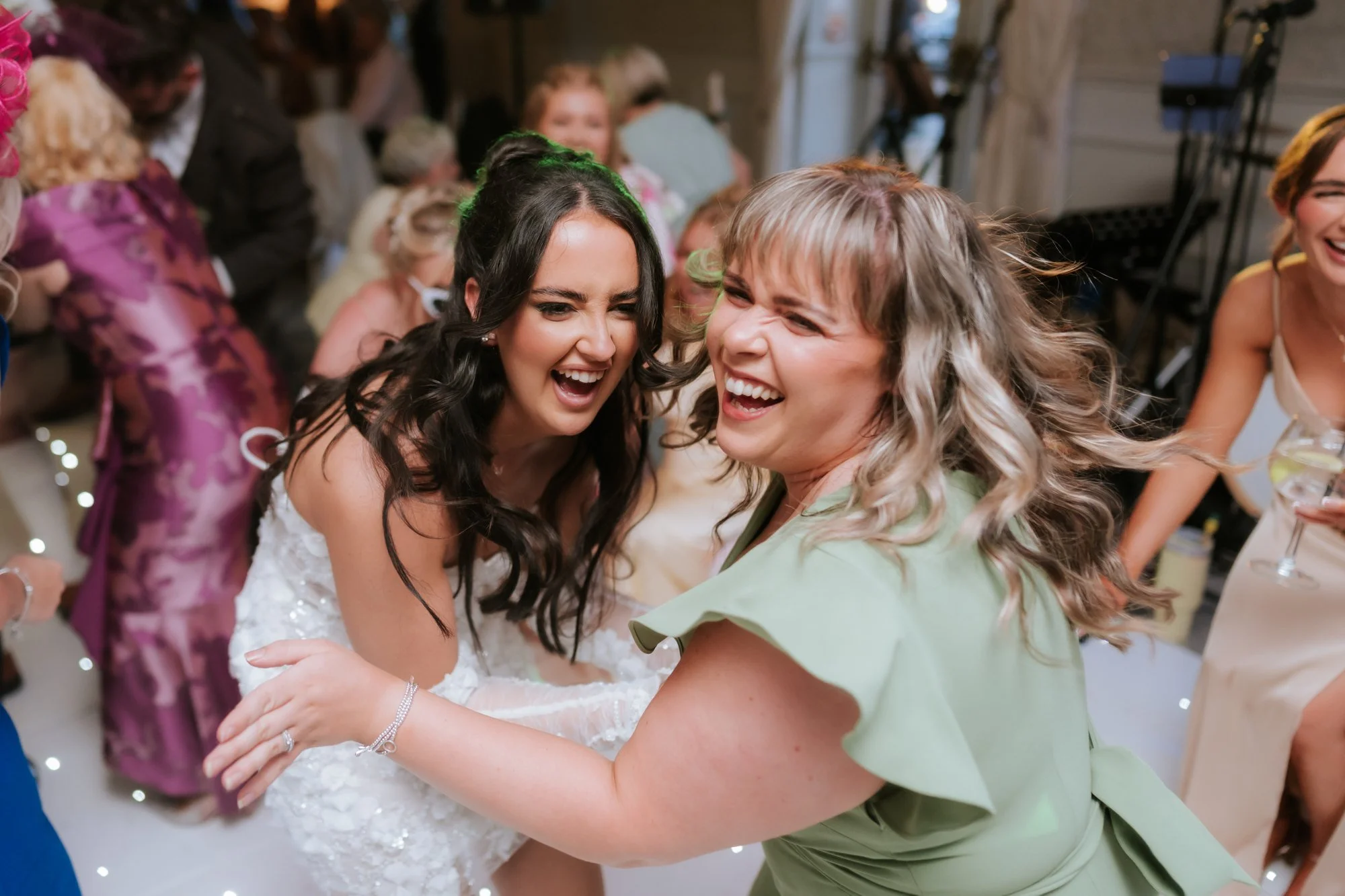 Kaitlyn laughing and dancing with a guest in a green dress at Glenbervie House.