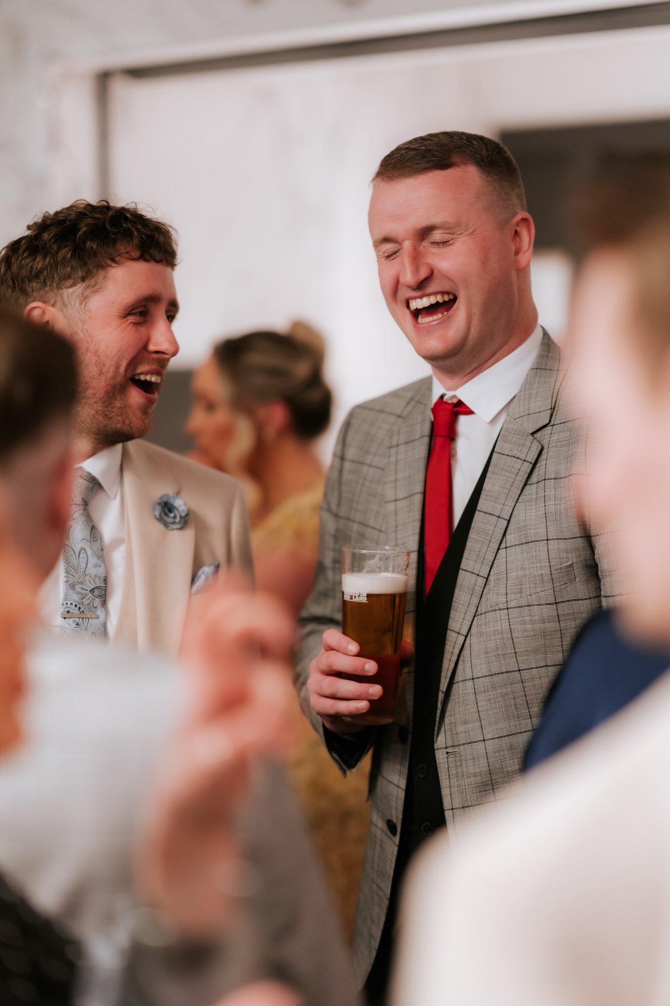 Two male wedding guests laughing together