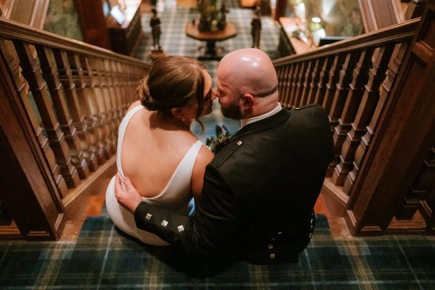 Kendall and Ewen looking at each other while sitting together on the hotel staircase.