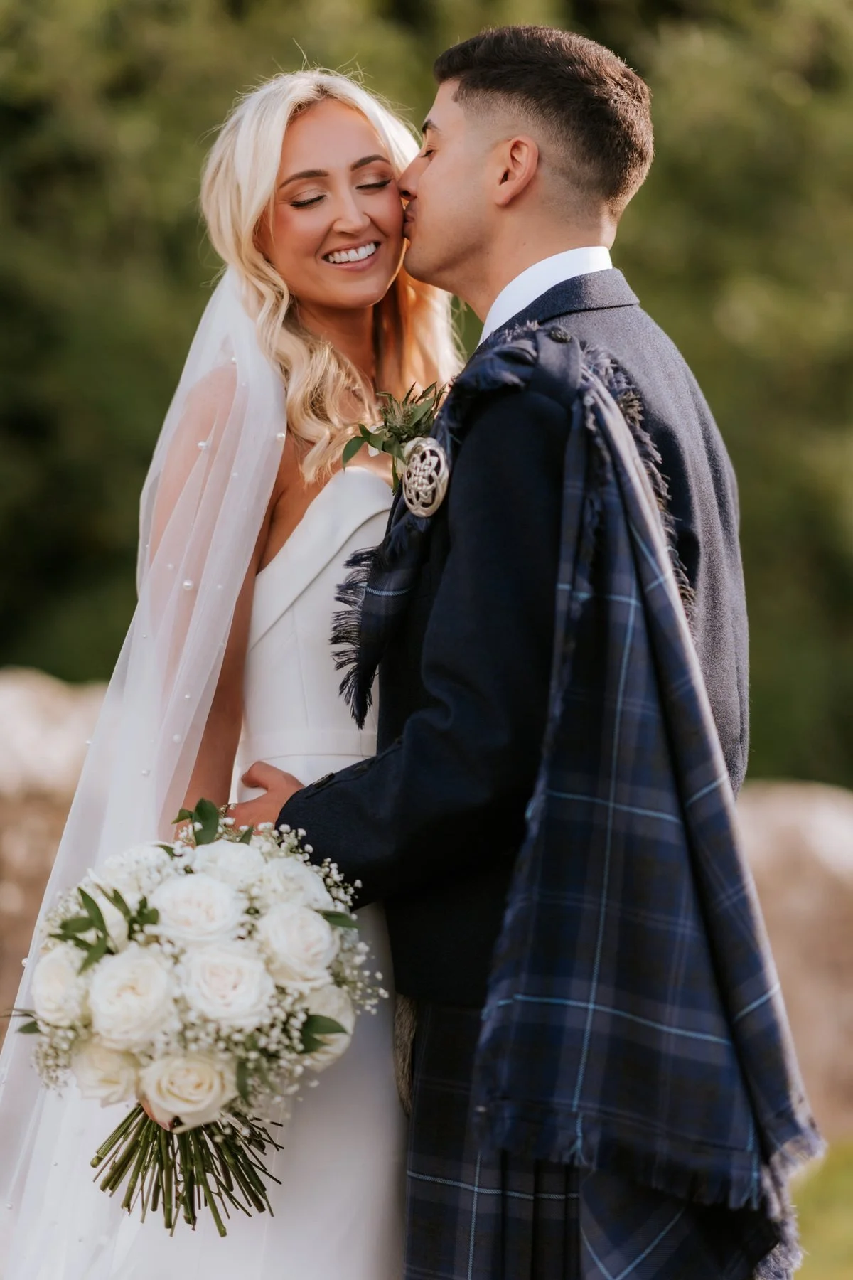 Zen kissing Lauren’s forehead as she smiles with her bouquet.