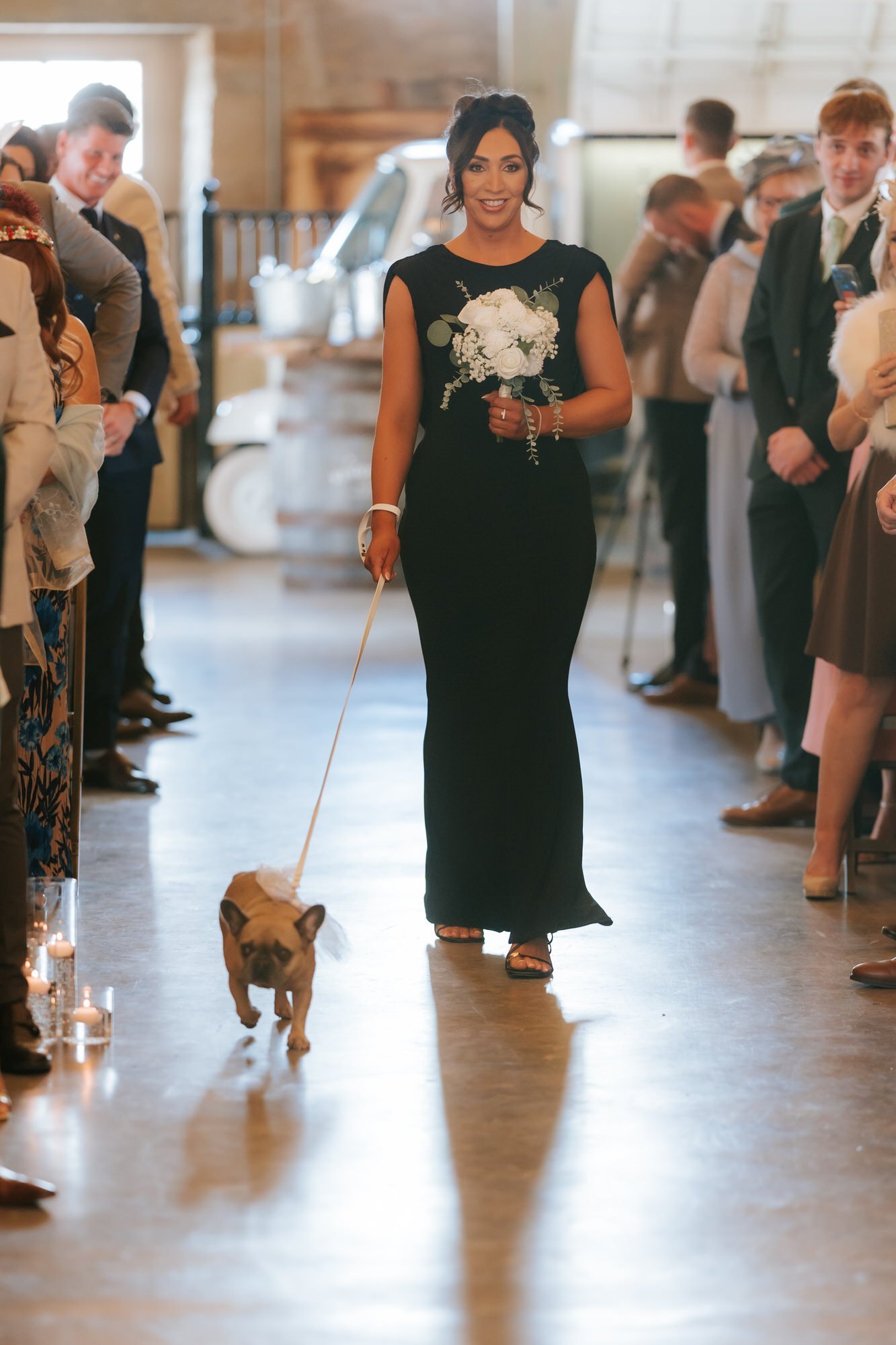 A bridesmaid walking a dog down the wedding aisle