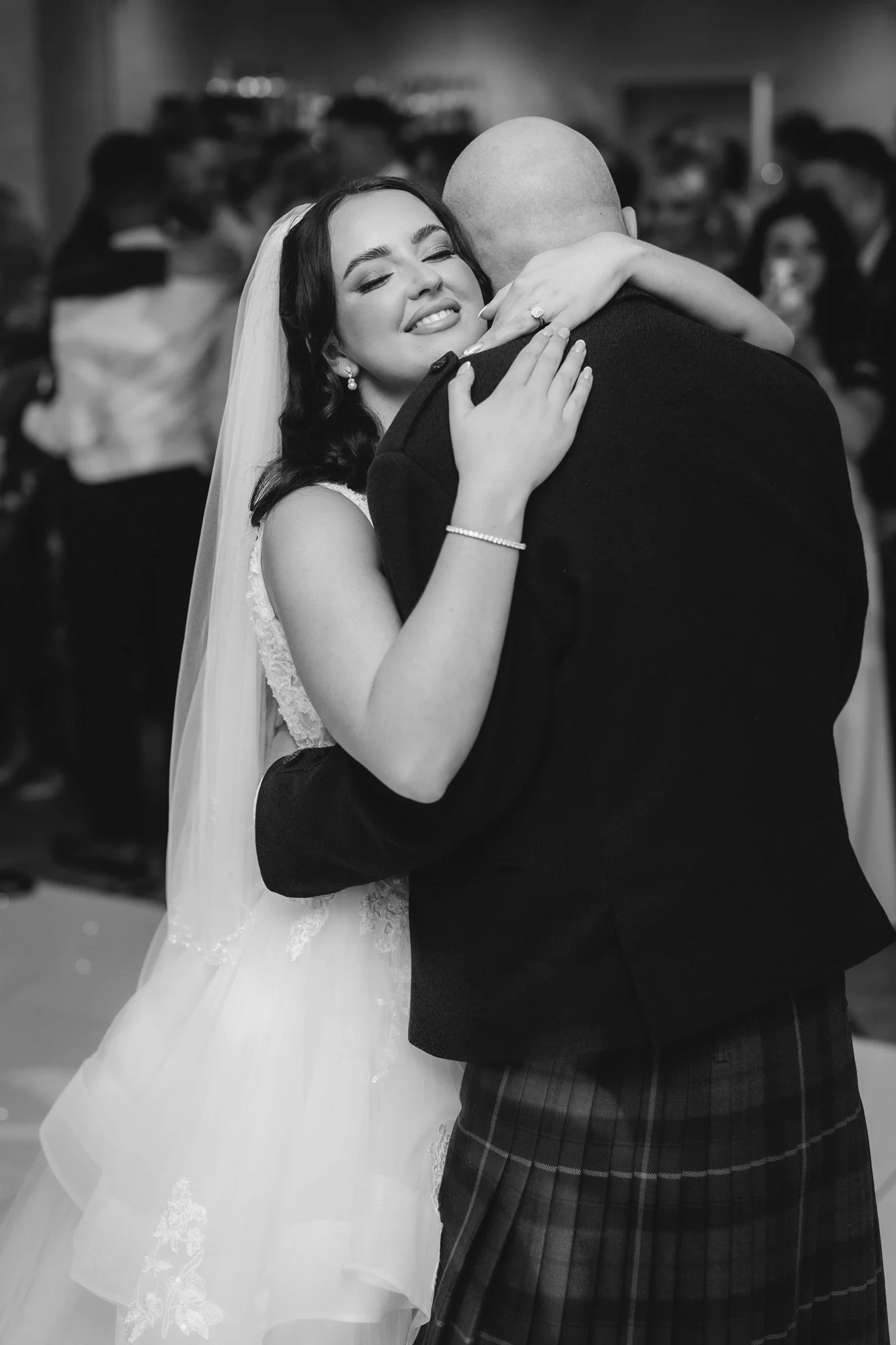 Black-and-white photograph of Kaitlyn embracing a guest on the dance floor at Glenbervie House.