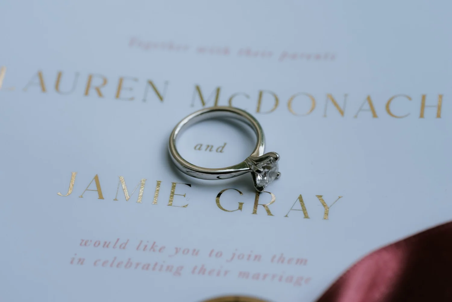 Wedding rings resting on Lauren and Jamie’s wedding invitation.