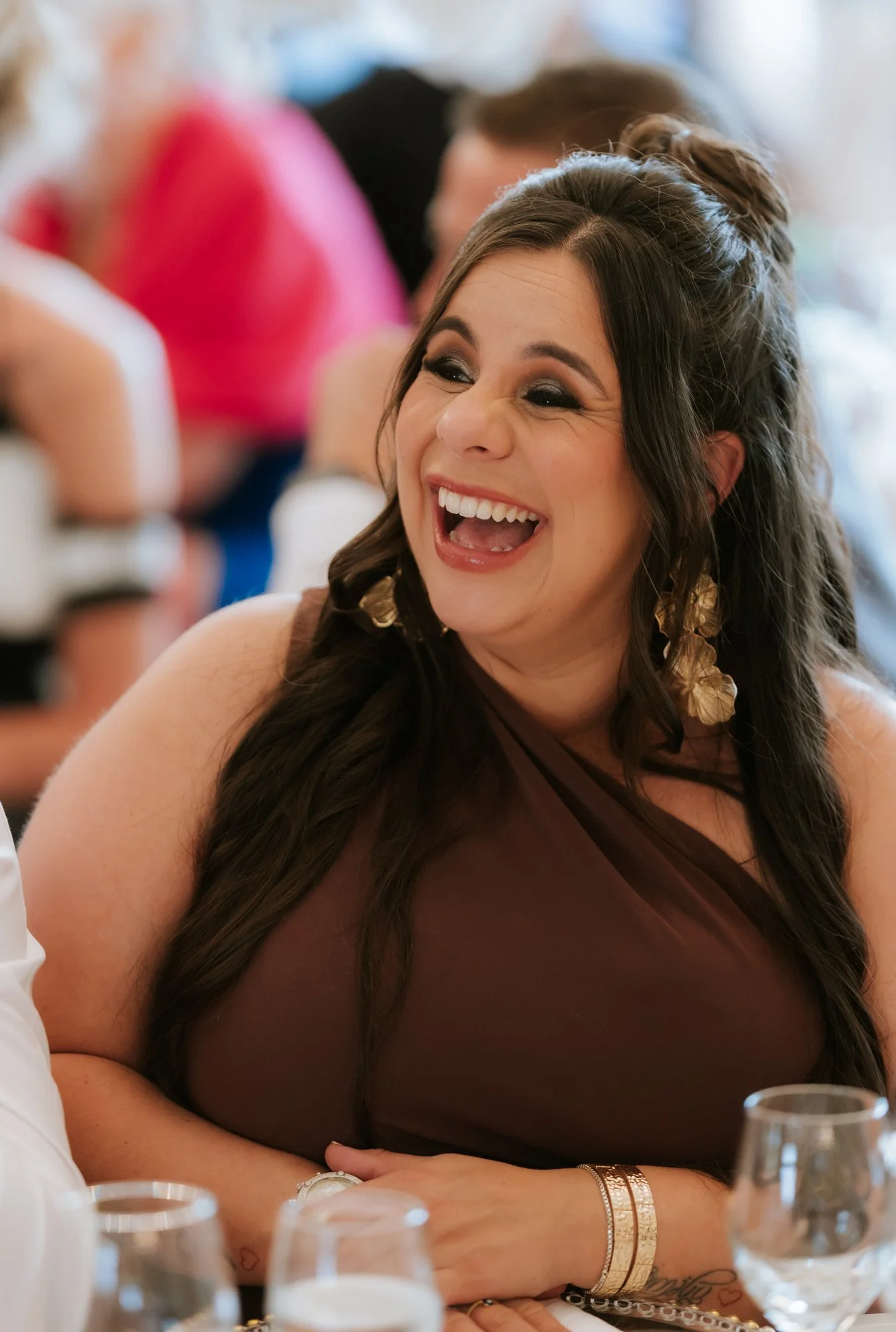A wedding guest in a brown dress laughing during the reception at Glenbervie House.