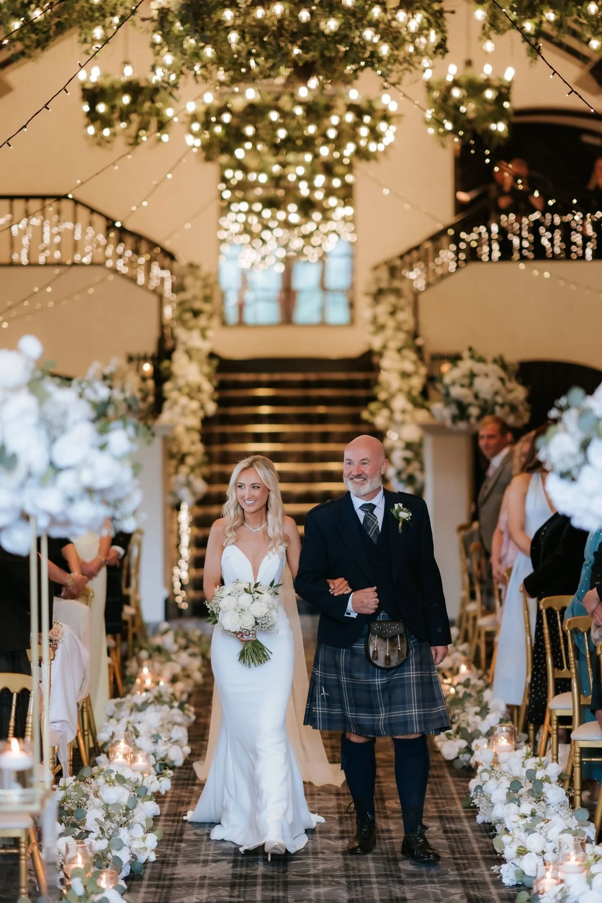 Lauren walking down the flower-lined aisle with her dad at Brig o’ Doon.