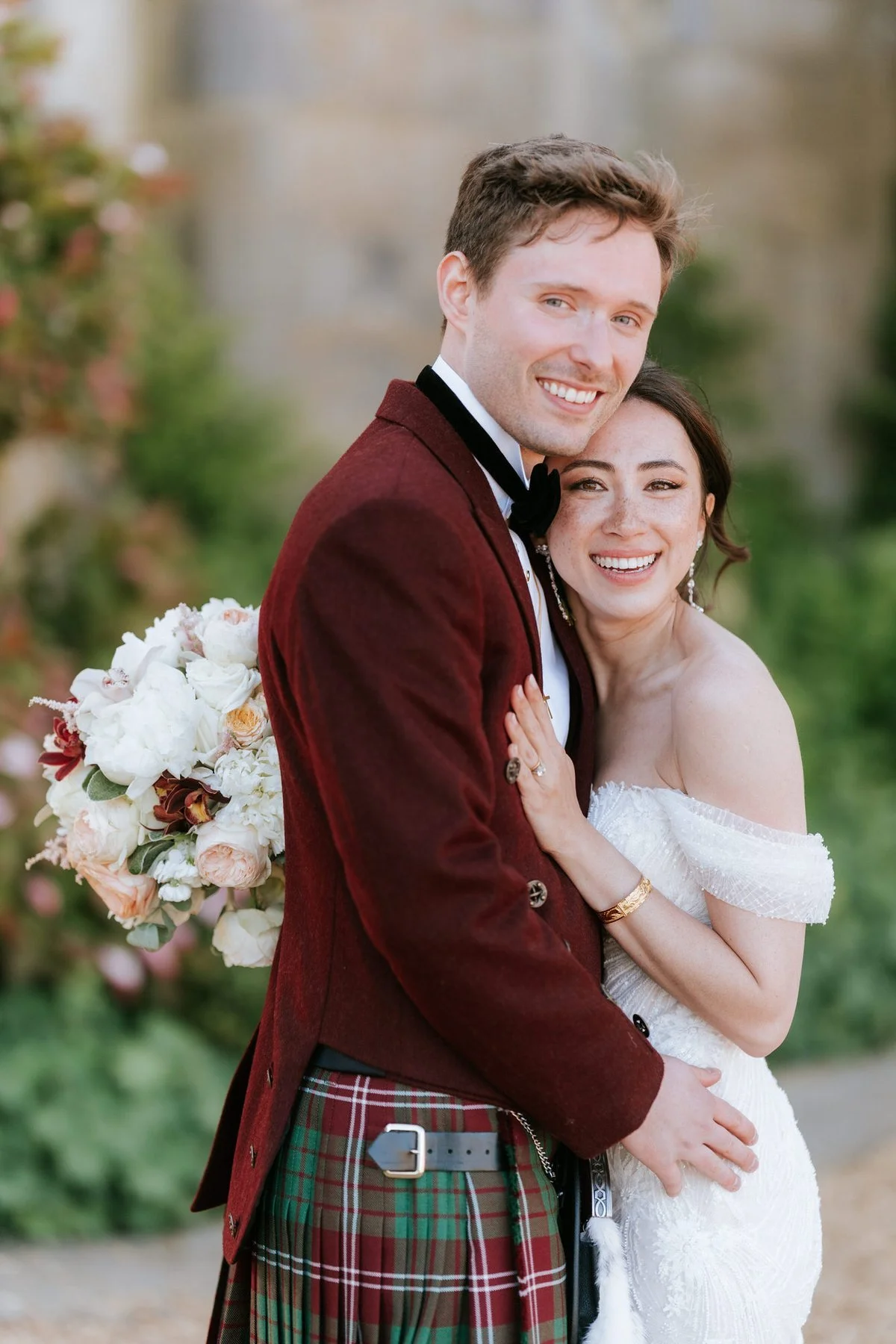Kim and Kenneth smiling together, with Kenneth in his burgundy jacket and tartan kilt.
