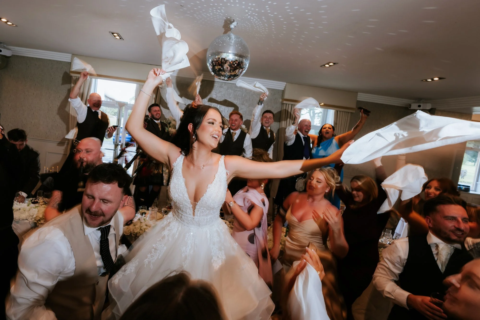 Kaitlyn waving white napkins with friends and family at the wedding breakfast at Glenbervie House.
