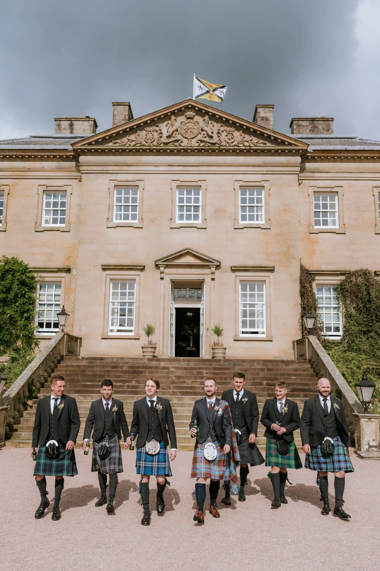 Jamie and his groomsmen in tartan kilts in front of Dumfries House.