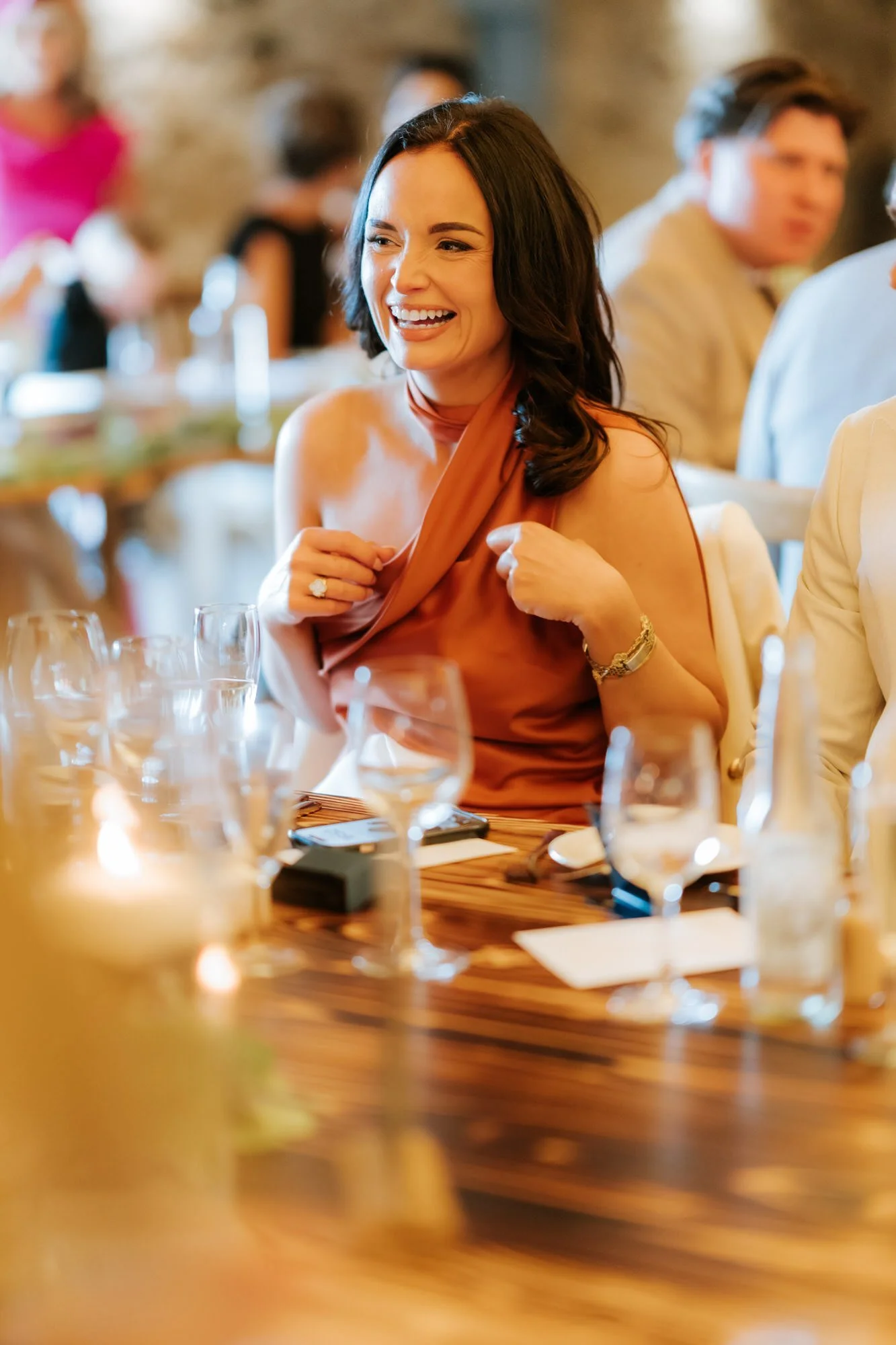 A guest in a rust-coloured dress laughing at the table