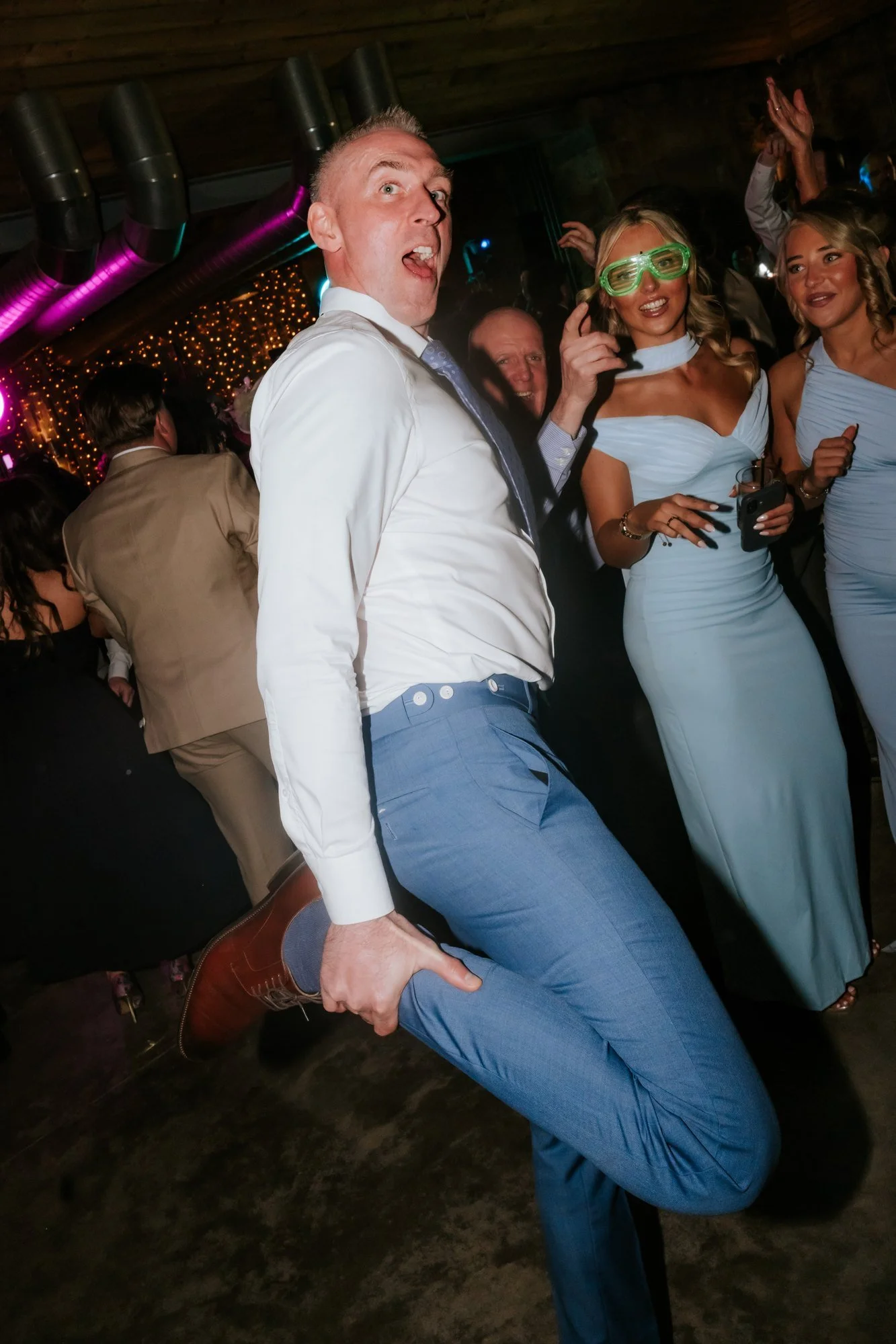 A wedding guest jumping with his knees bent on the dance floor