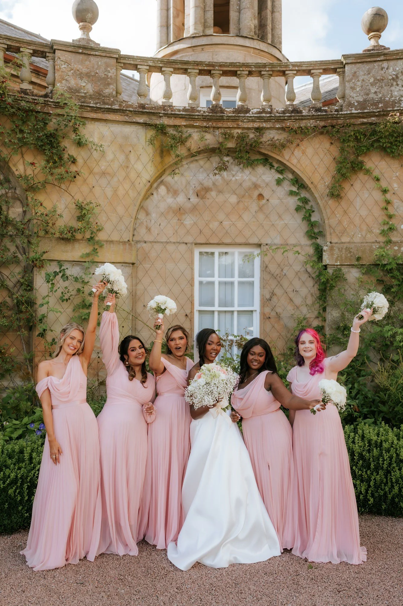 The bridal party celebrating with their bouquets in the air.