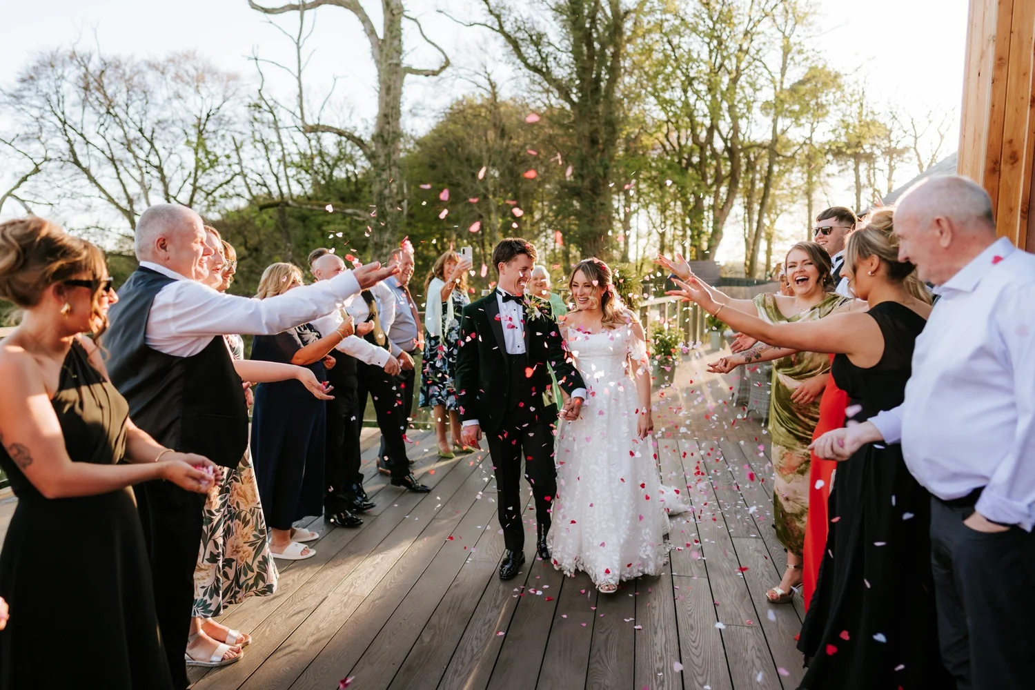 Ciara and Jonathon walking through colourful confetti on the decking at Enterkine House.