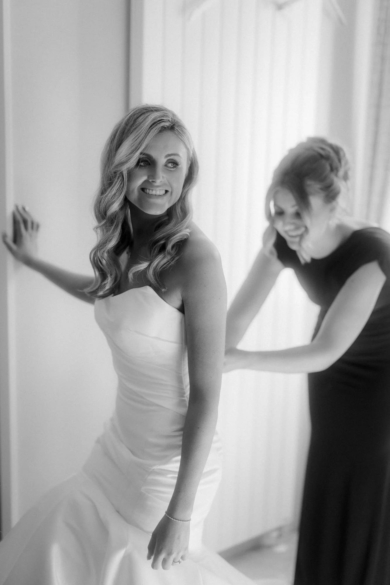 Black-and-white photograph of laughter while Natalie's dress is fastened