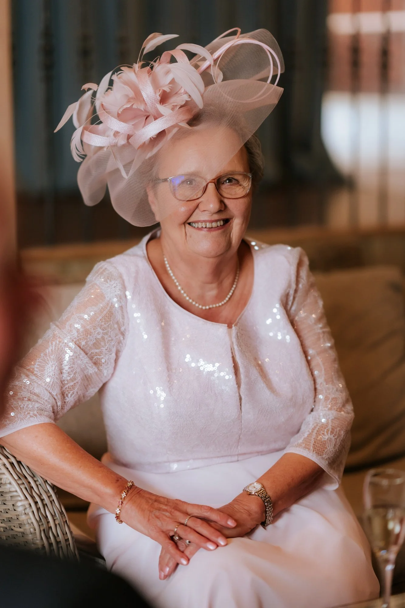 A wedding guest in a pink hat smiling during the reception.
