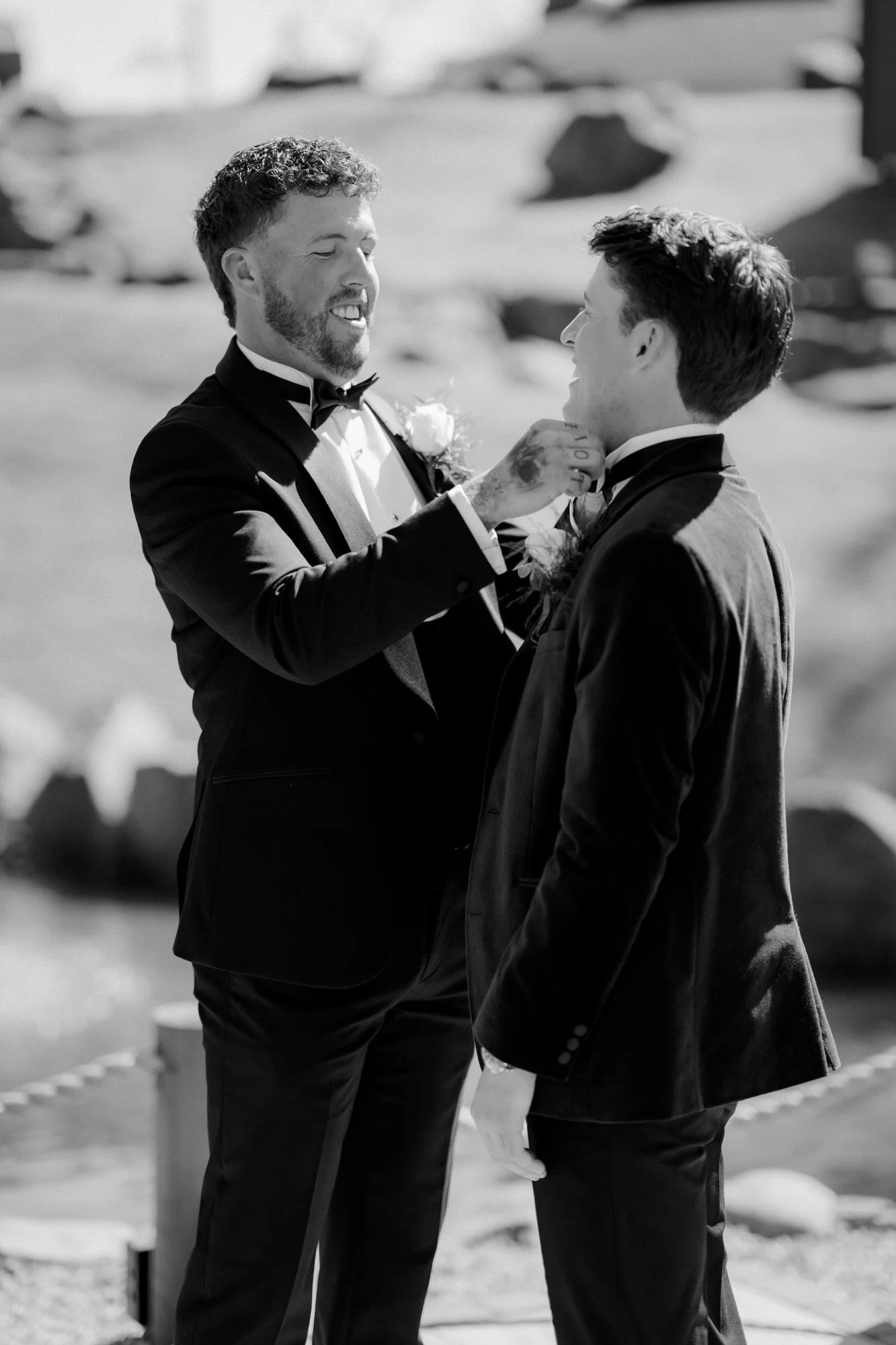 A groomsman helping Jonathon with his bow tie.