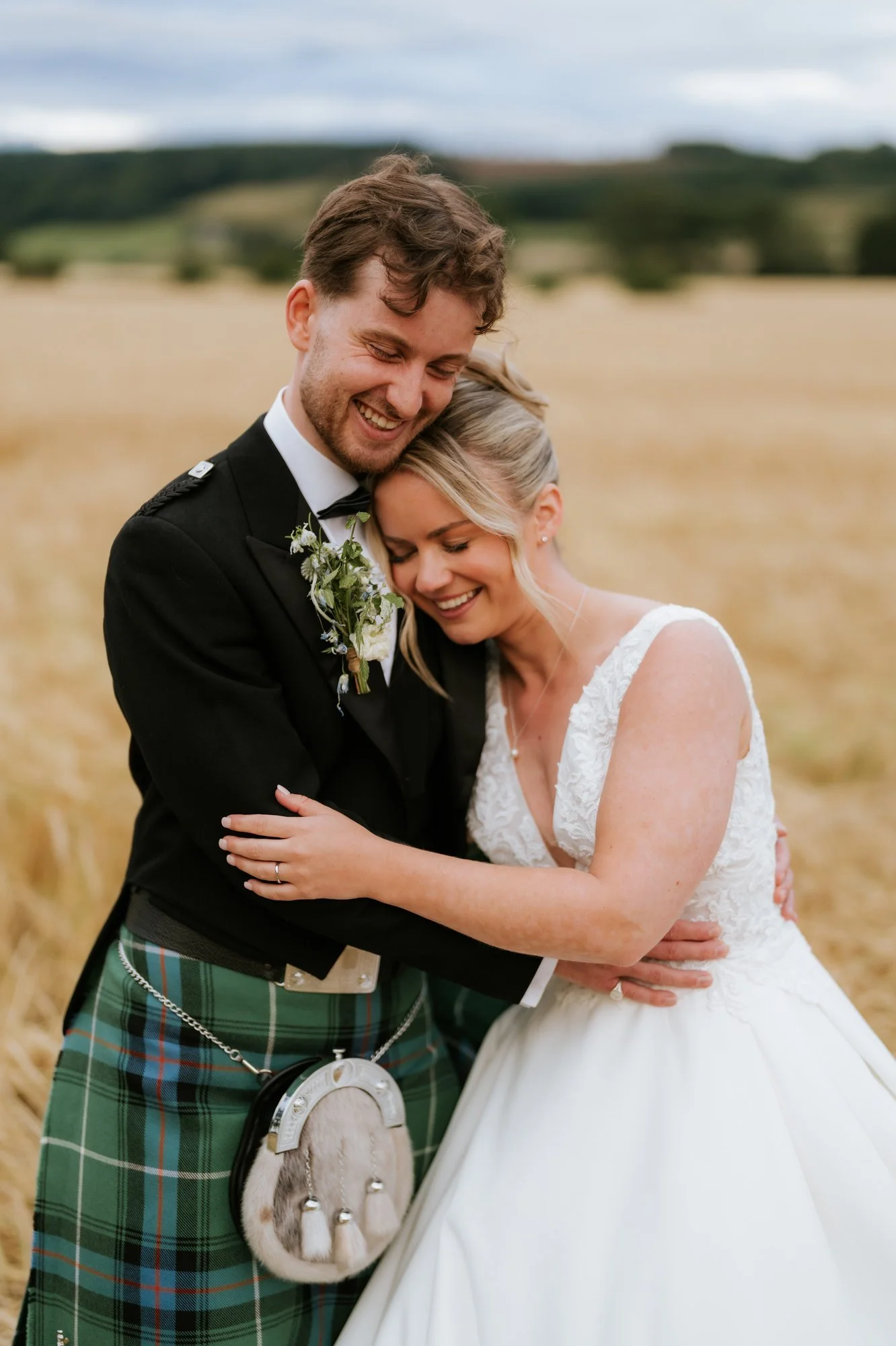 Lilian leaning into Luke as they laugh together beside the golden fields.