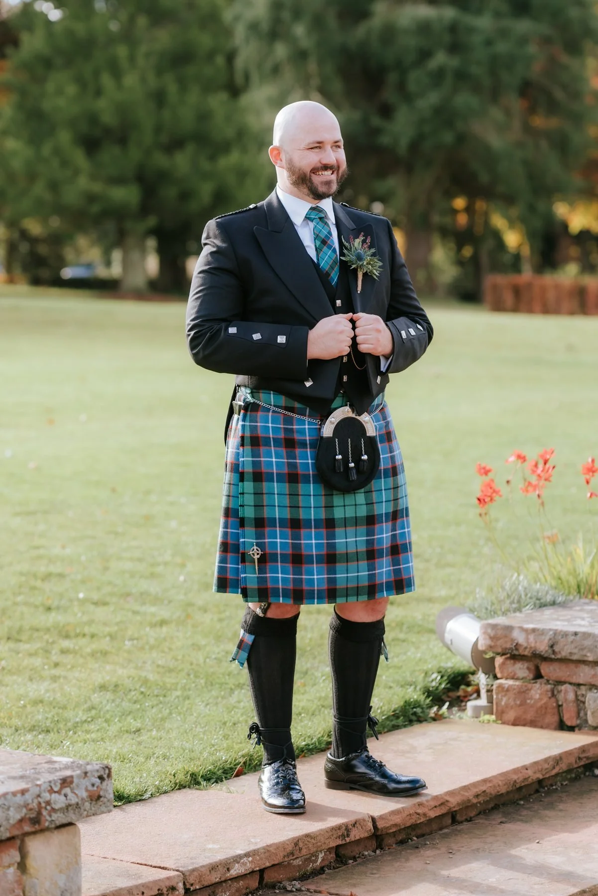 Ewen standing on the garden steps in his kilt and black wedding jacket.