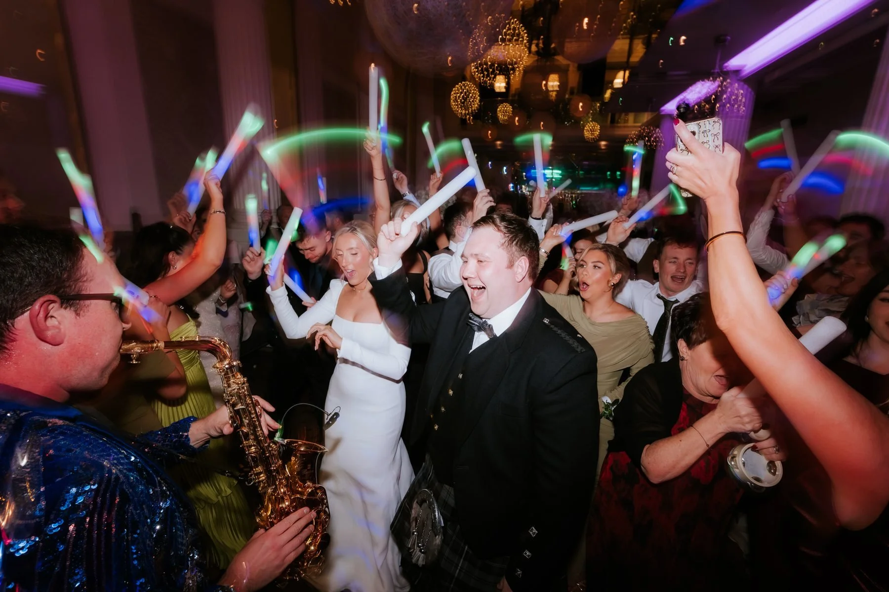 Jordan and Jen celebrating among raised light-up sticks during the saxophone set.