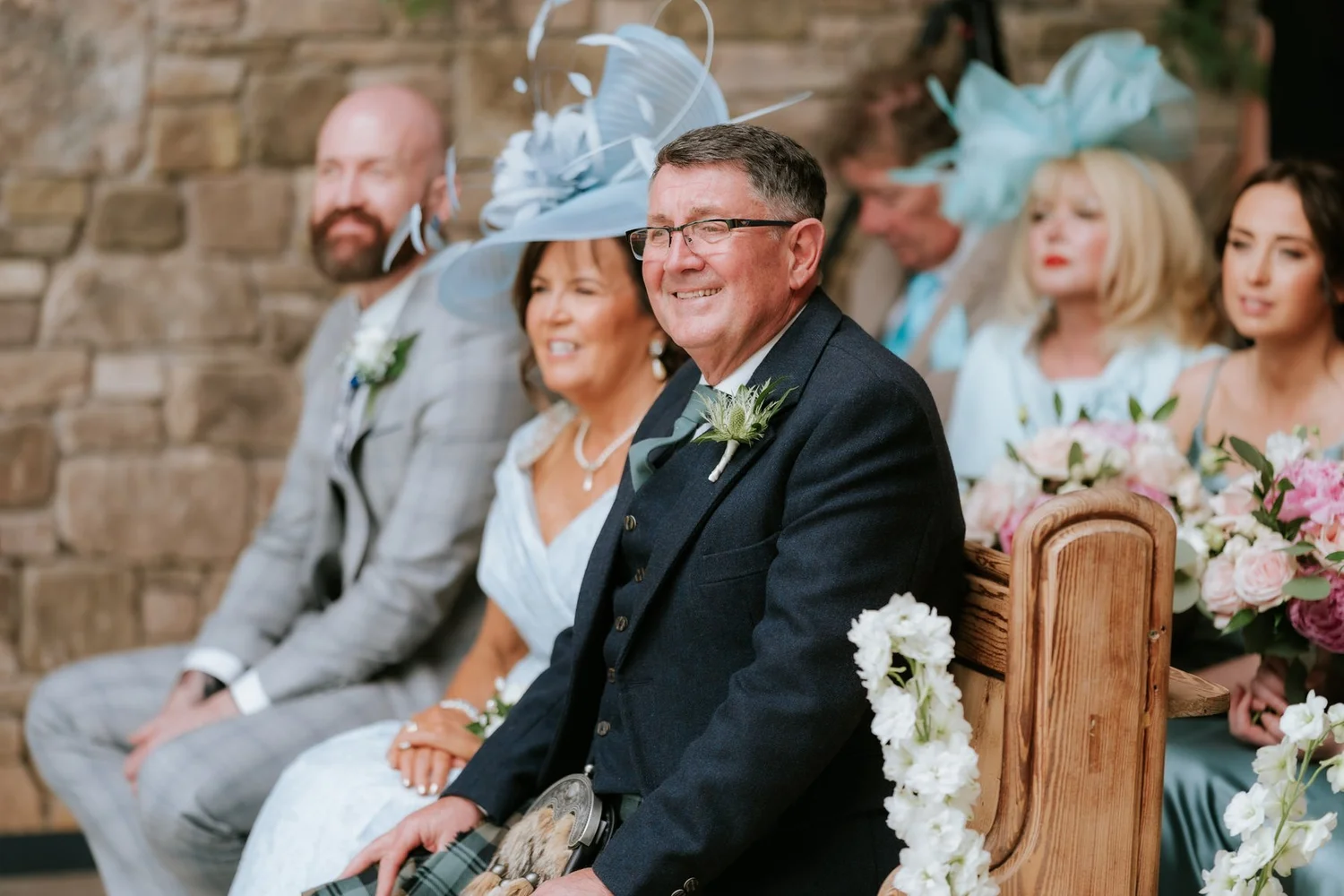 Wedding guests laughing together in the front row during the ceremony at Cairns Farm.