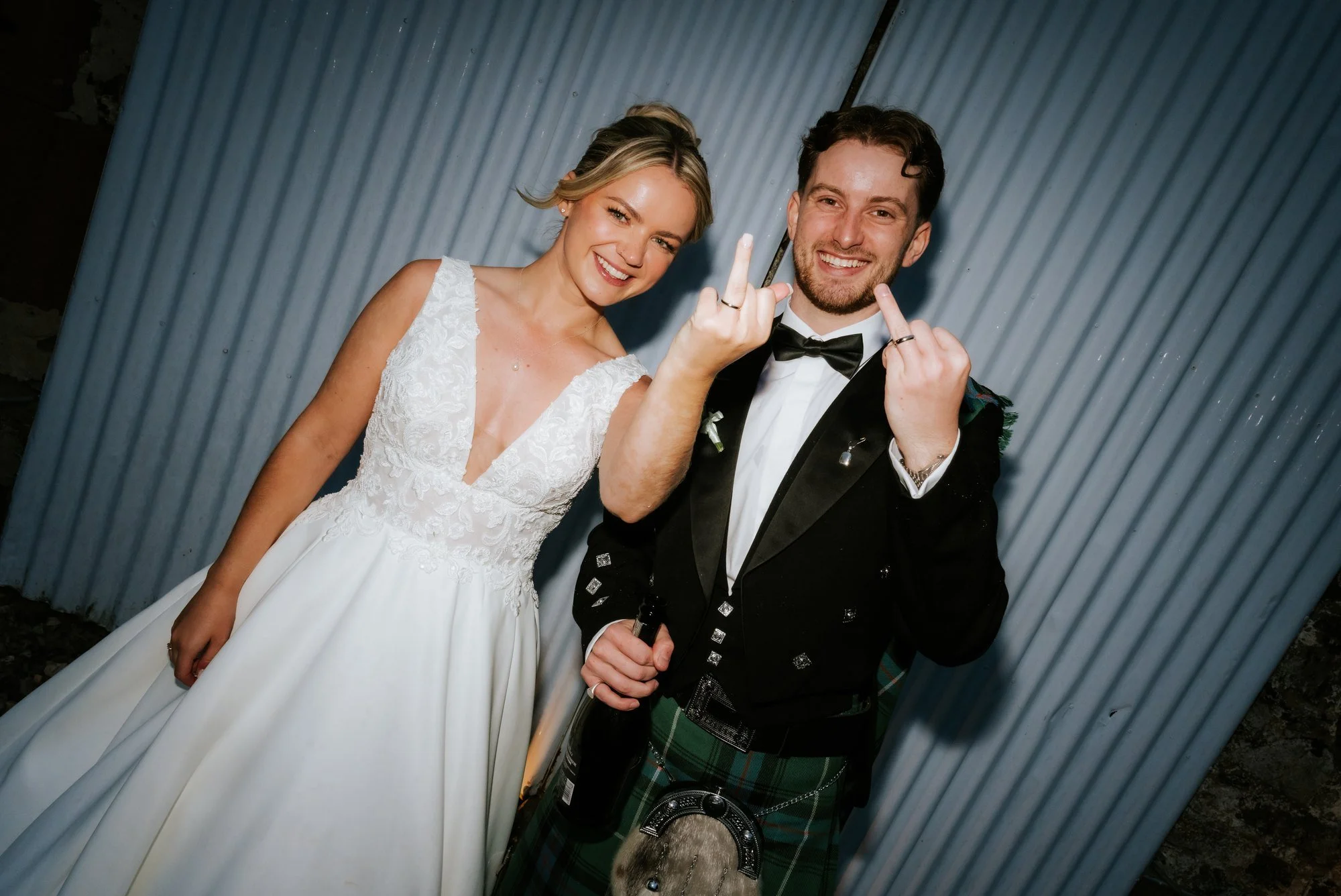 Lilian and Luke showing their wedding rings and laughing outside the reception.
