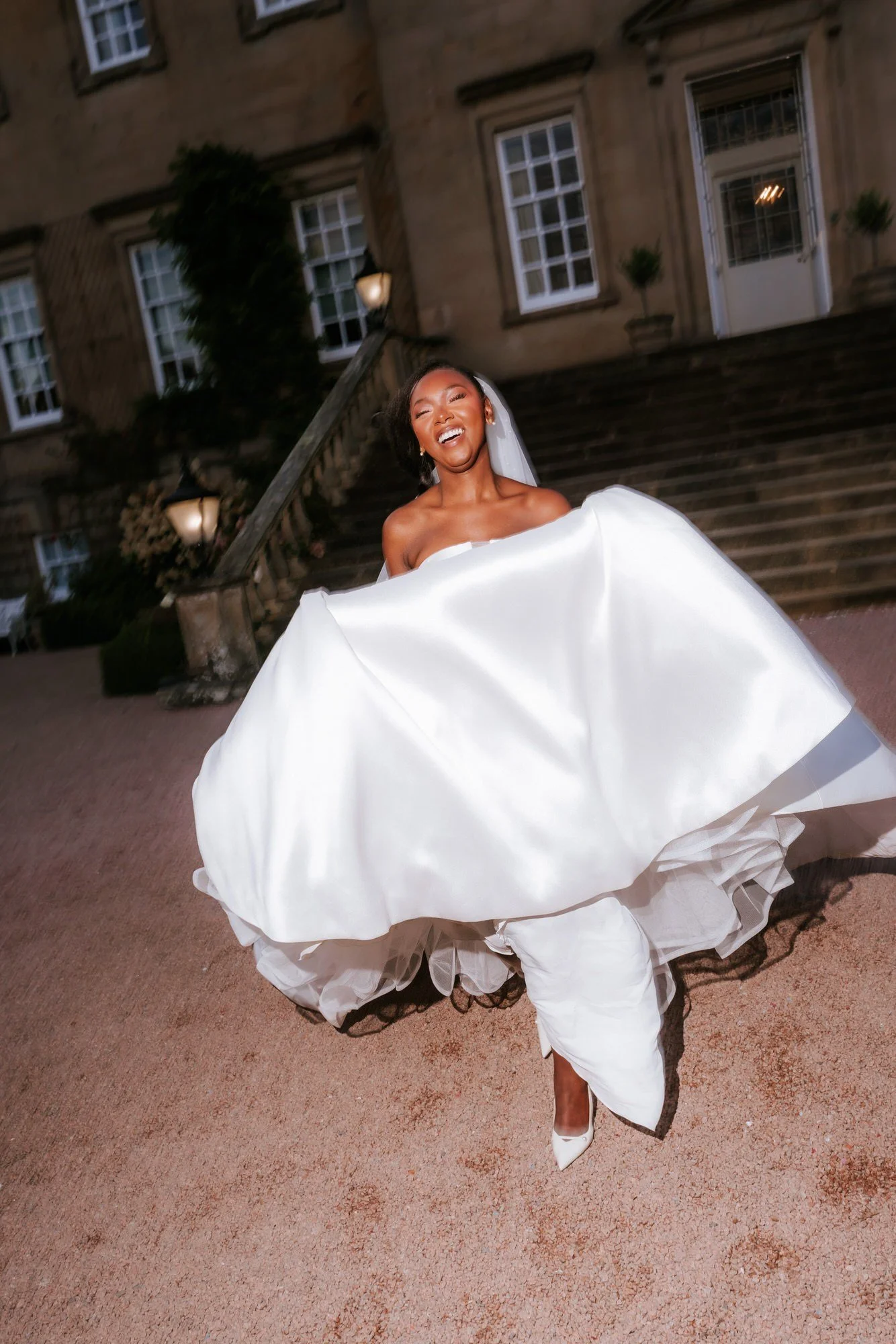 Kuda laughing as she lifts her dress in front of the house.