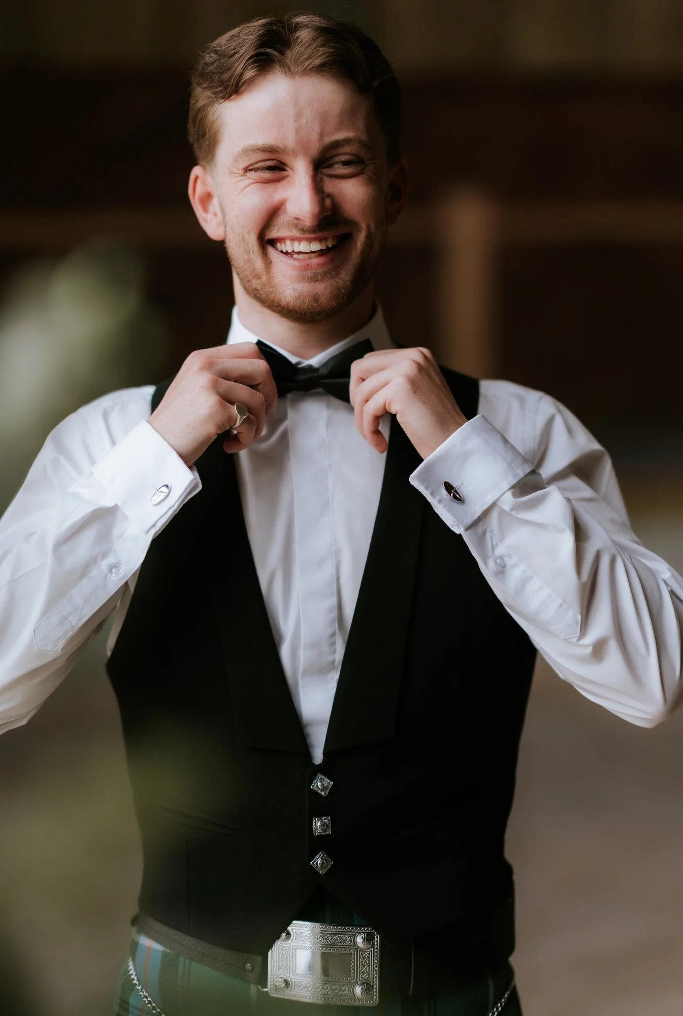 Luke laughing as he adjusts his bow tie during preparations.