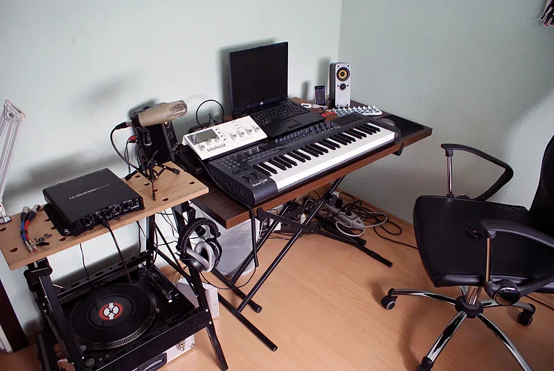 A compact home recording workspace contains a keyboard, computer, speakers and microphone.