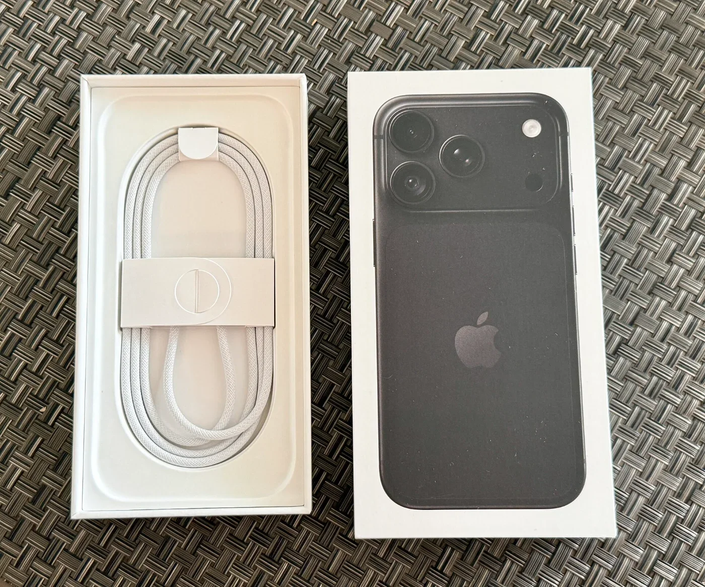 A black iPhone 18 Pro and its cable sit in an open retail box.