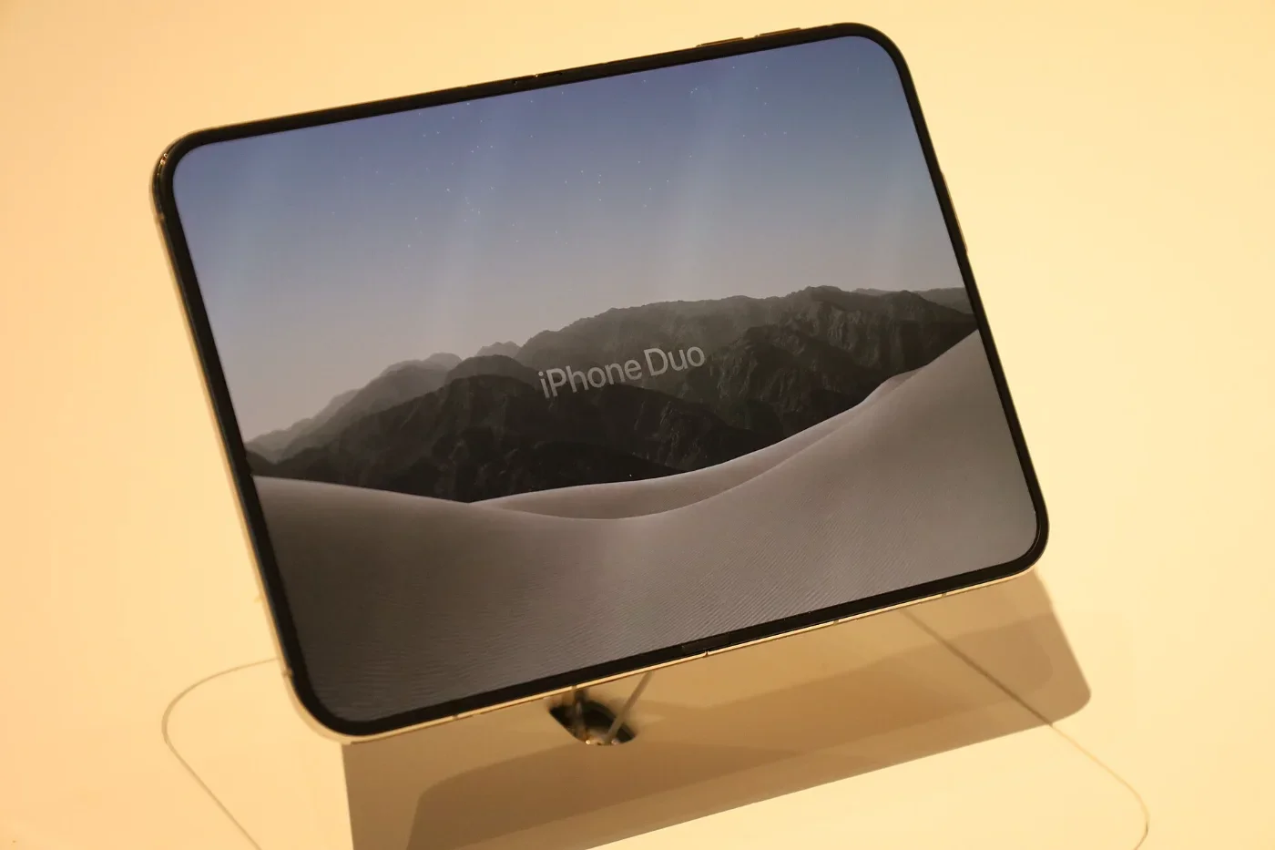 An unfolded iPhone Duo sits on a retail display stand.