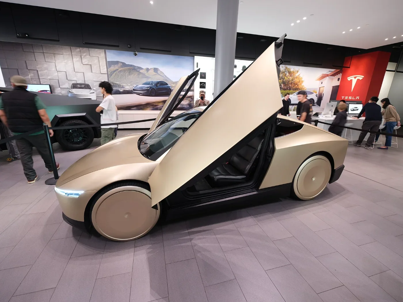 A gold Tesla Cybercab is displayed with its door raised.