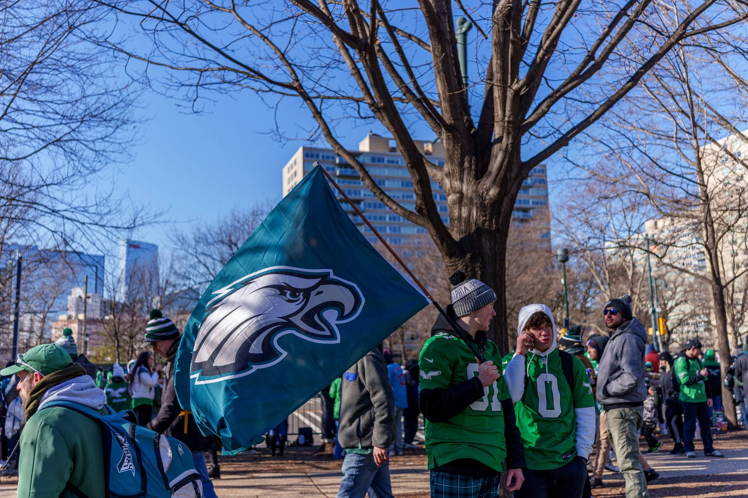 Fans waving a large Eagles flag under the trees