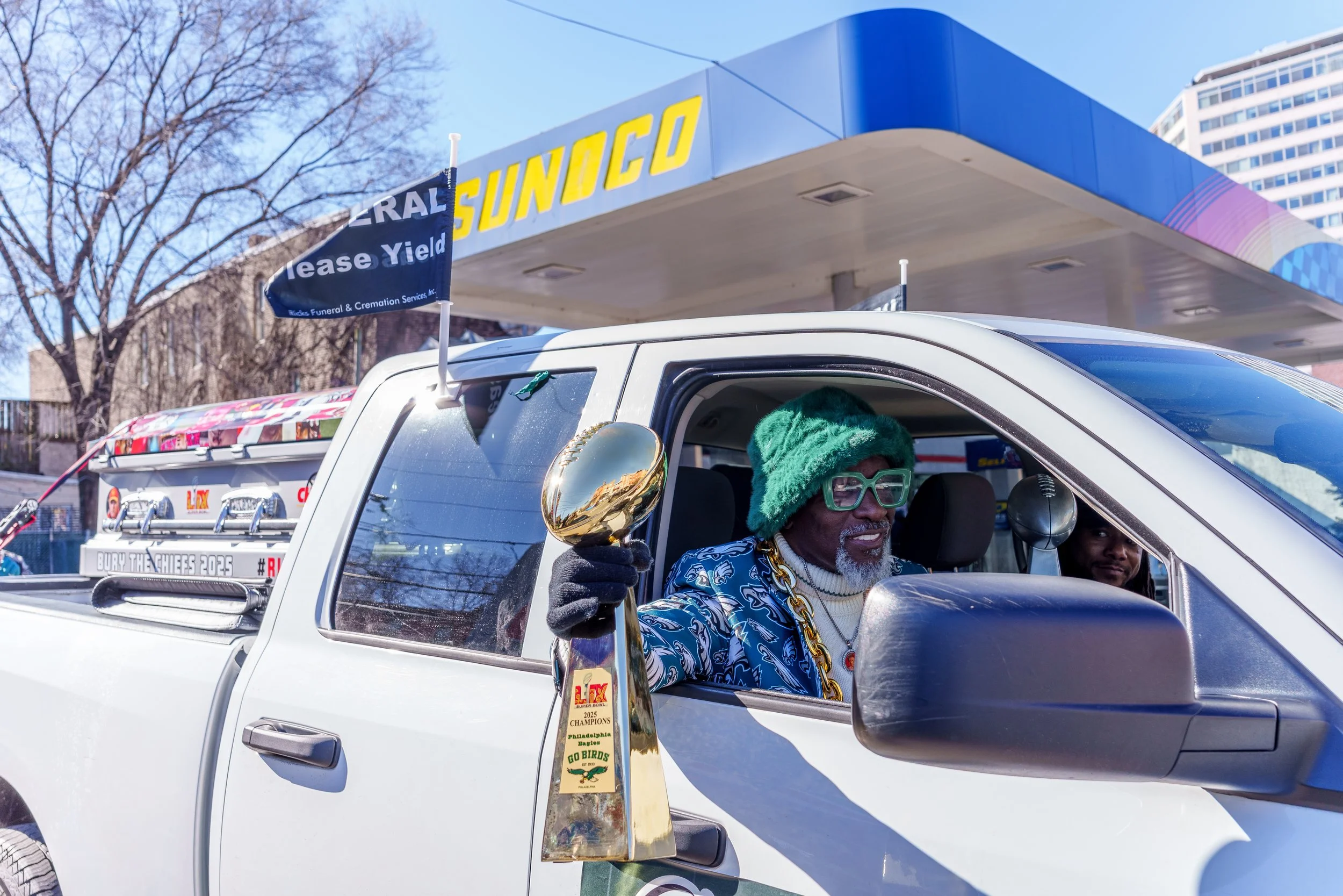 Fan holding a championship trophy replica from a truck window