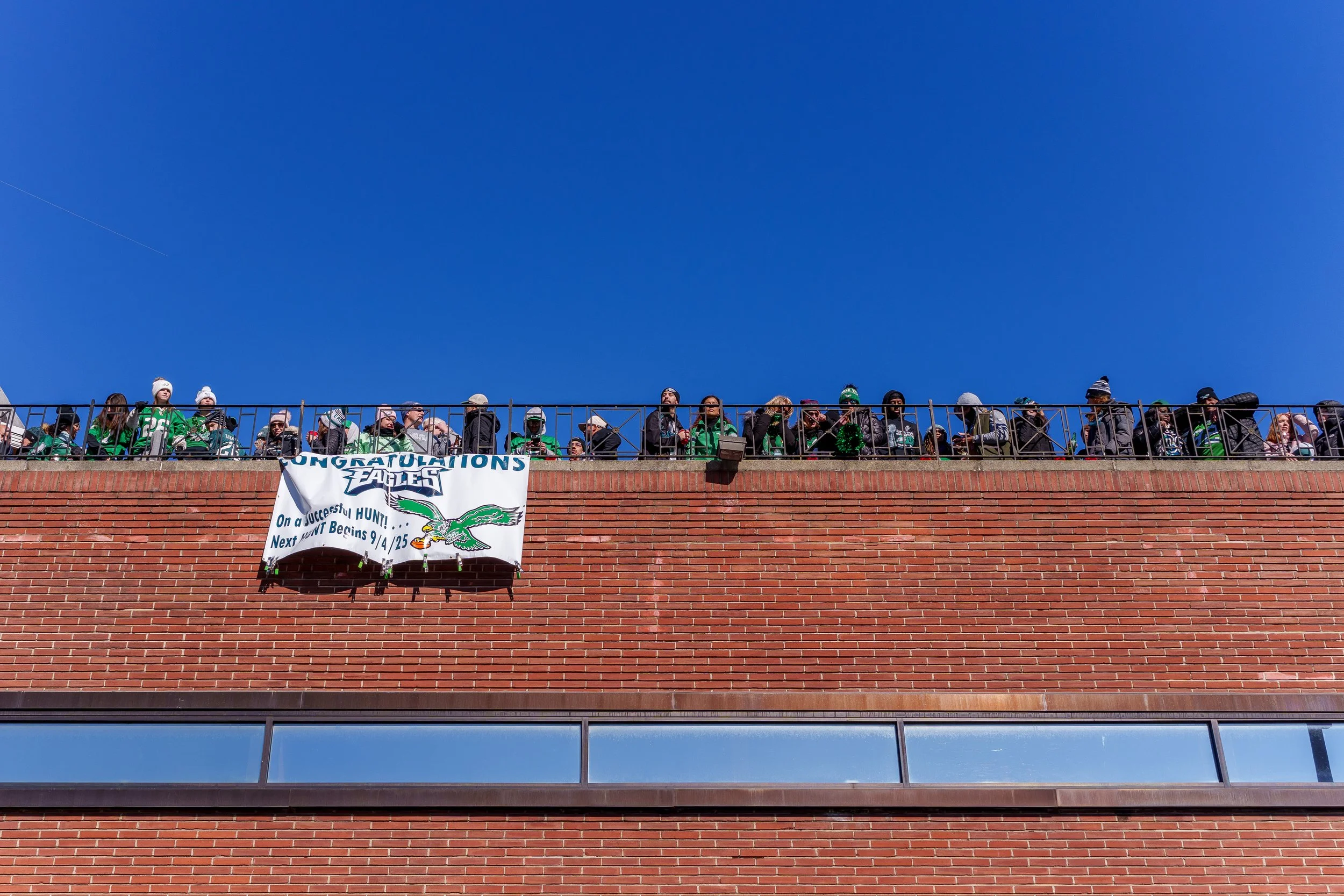 Fans lining a rooftop beneath a Congratulations Eagles banner
