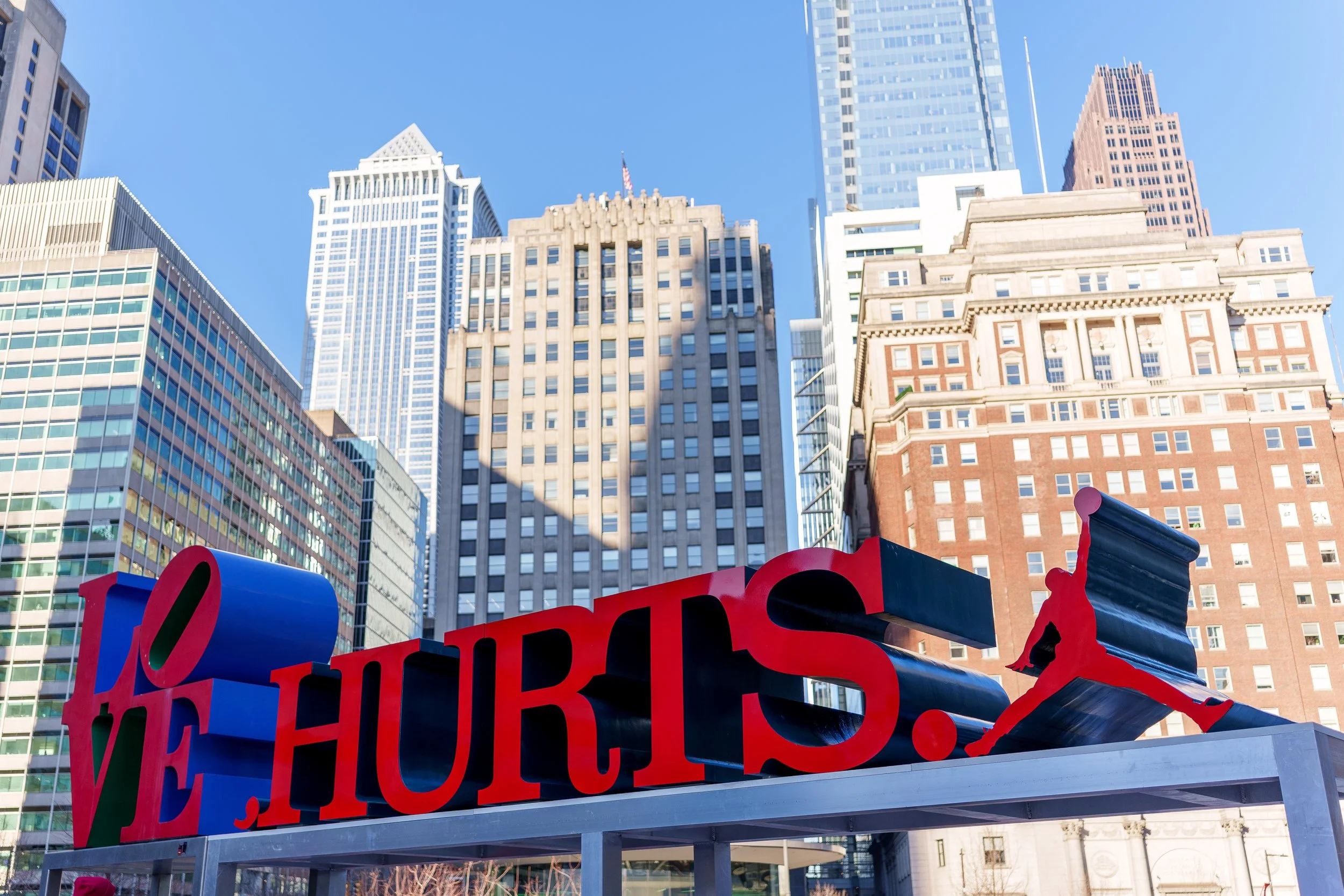 LOVE HURTS. sculpture at Love Park against the Philadelphia skyline