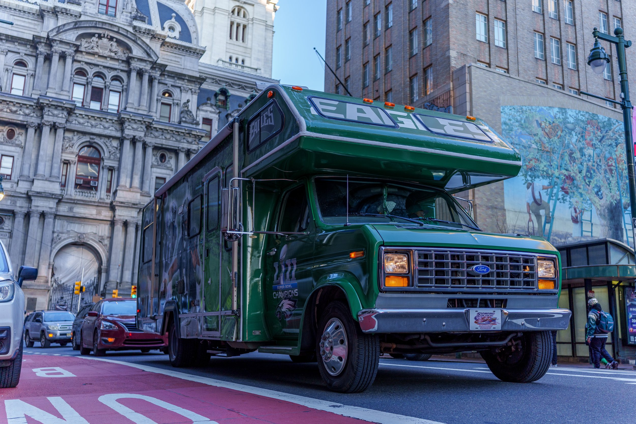Fans walking past a green Eagles wrapped shuttle near City Hall