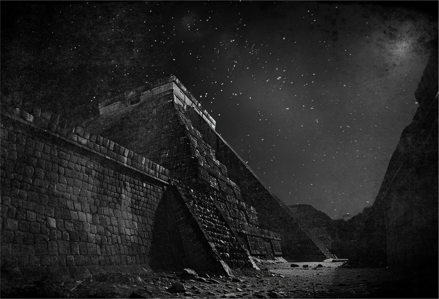 Black and white photo with film grain depicting an ancient South American style stone pyramid in a barren landscape under a star speckled sky at night.