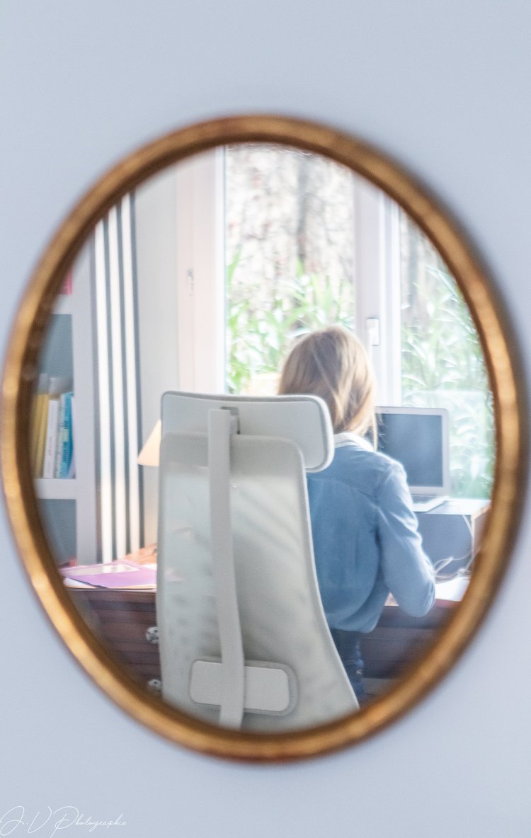 Violaine de dos à son bureau, vue dans un miroir rond