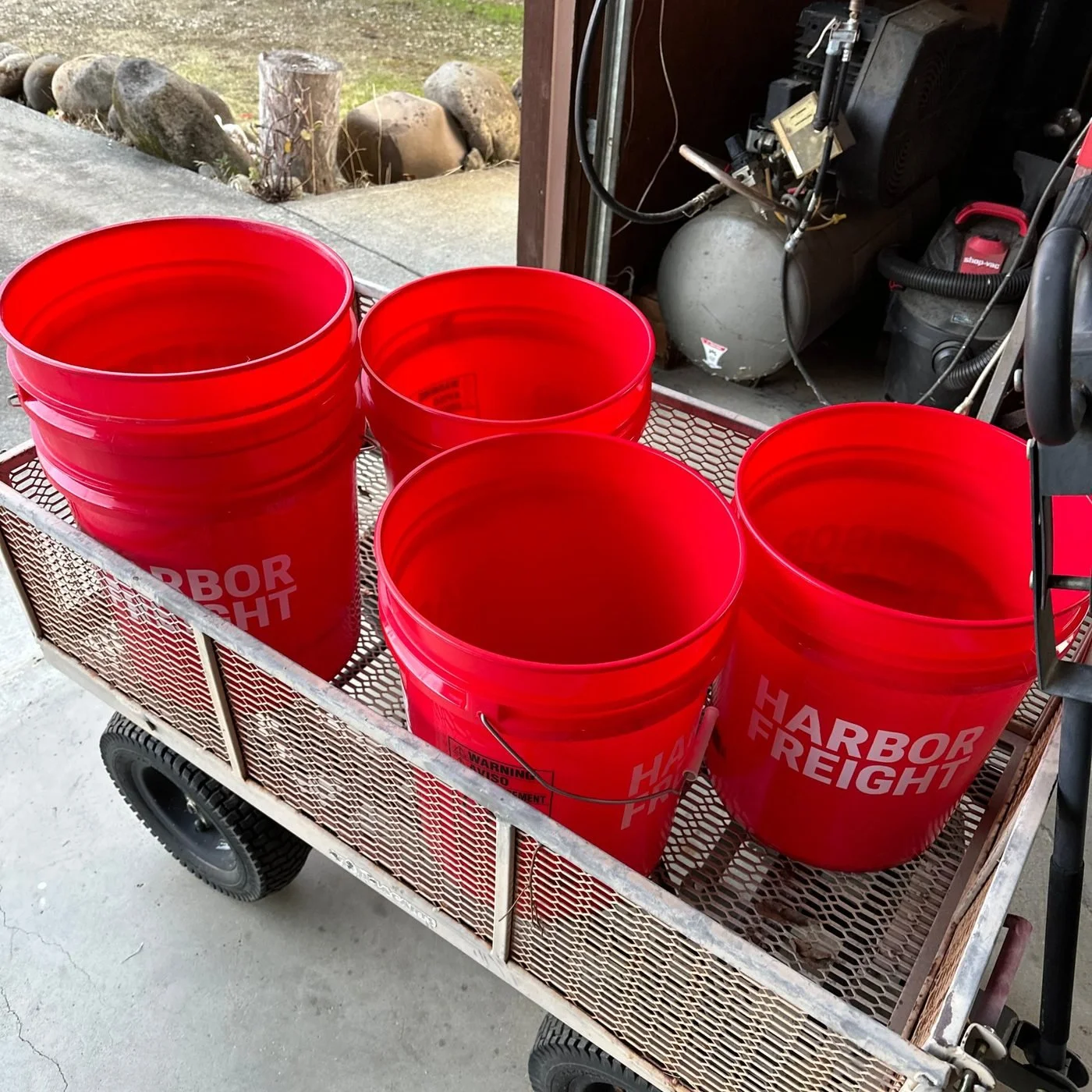 Four empty red 5-gallon buckets loaded on a garden cart, ready for a trip