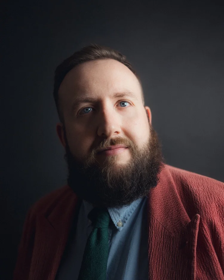 Hugo Herman-Wilson in a coral jacket against a dark background