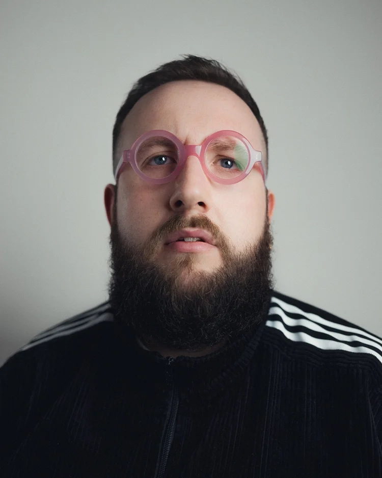 Hugo Herman-Wilson in a black track top and pink glasses
