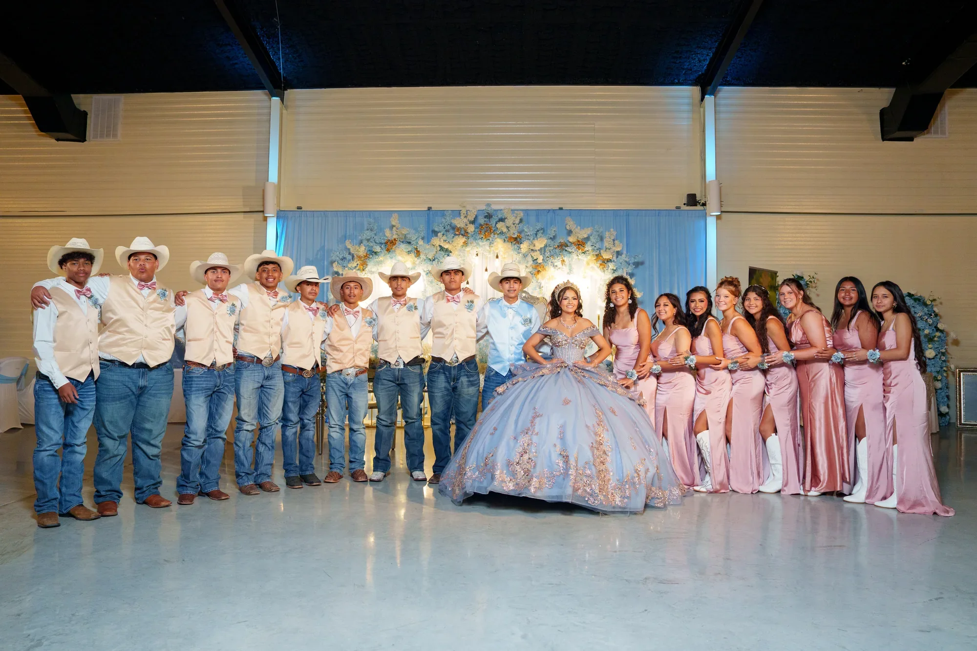 La corte completa de la quinceañera en el salón, chambelanes vaqueros y damas de rosa