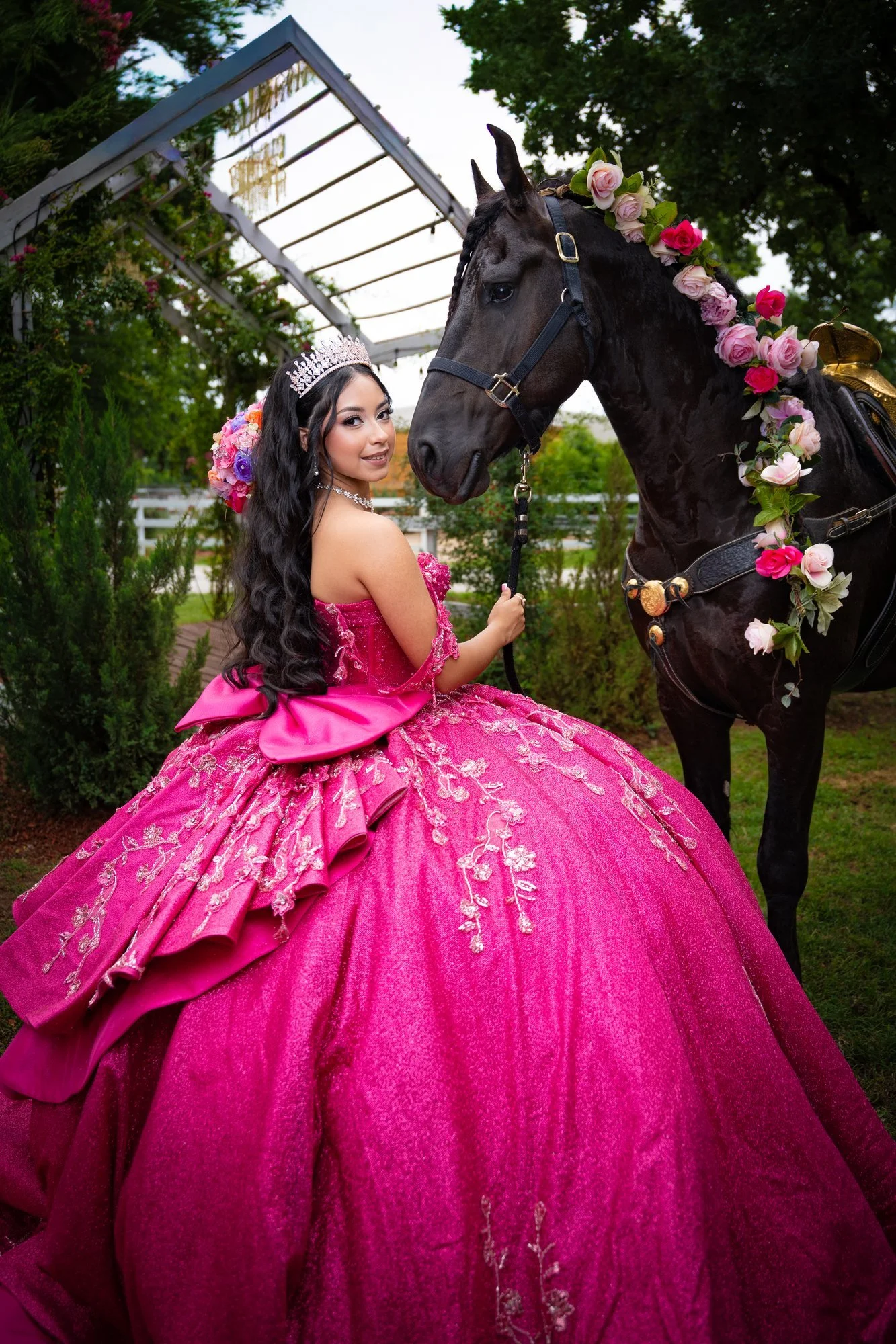 Quinceañera con vestido magenta junto a un caballo negro