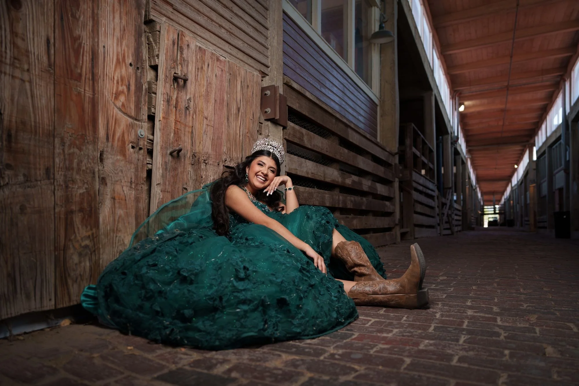 Quinceañera con vestido verde en los Fort Worth Stockyards para una sesión de fotos con tema western